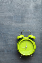 Green alarm clock on a grey wooden table