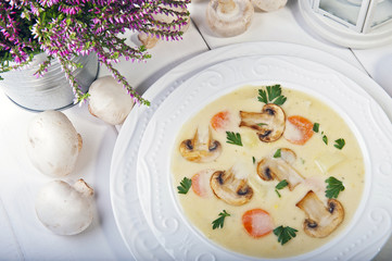 Champignon soup with parsley, carrots and potatoes on a white wooden table