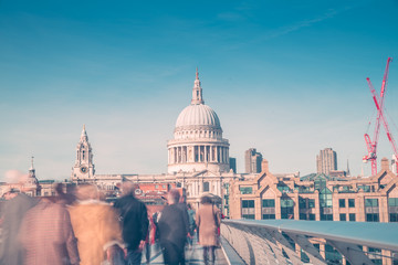 Fototapeta premium Unrecognizable people walking over Millennium Bridge on a sunny spring day in London,UK. St Paul Cathedral in the background.