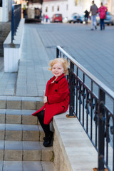 Portrait of a beautiful little girl with red hair in a red coat
