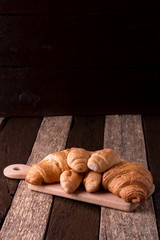 Croissants on board on wooden background. Rustic style.