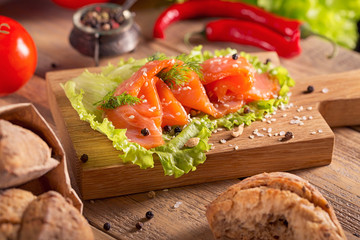 Slices of smoked salmon with dill, chile pepper, tomatoes and bread