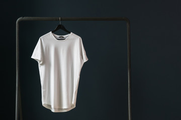 T-shirt with short sleeves on a hanger against the background of a dark wall.