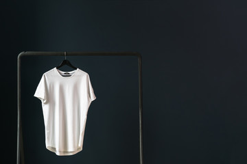 In the left part of image white empty T-shirt with short sleeves on a hanger.