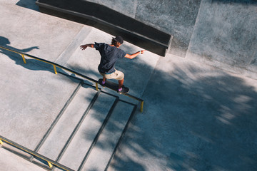 Young man - skater grind on a rail on his skateboard in a concrete skatepark