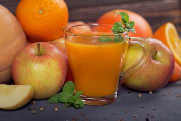 Fresh carrot, apple, pumpkin, orange, grapefruit on dark table.