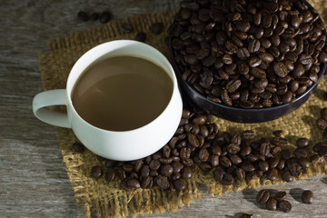 Coffee cup with coffee beans placed on the table,.On dark wood