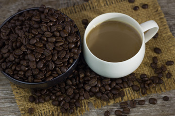 Coffee cup with coffee beans placed on the table,.On dark wood