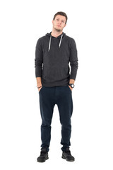 Fototapeta premium Relaxed young sporty man in hooded sweatshirt and sweatpants looking at camera. Full body length portrait over white studio background.