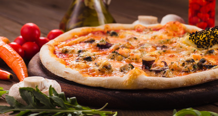 delicious Italian seafood pizza with ingredients on wooden table (close)