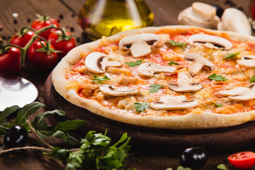 italian pizza with chicken and mushrooms on the wooden dark background with ingredients around (close)