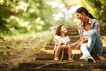 Mother holding her daughter and playing around the park on beautiful day.