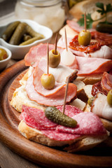 Tapas with sliced sausage, salami, olives and parsley.