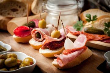 Tapas with sliced sausage, salami, olives and parsley.
