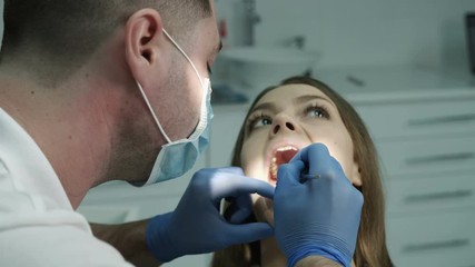 Dentist beginning the check up of his patient at the dentist cabinet