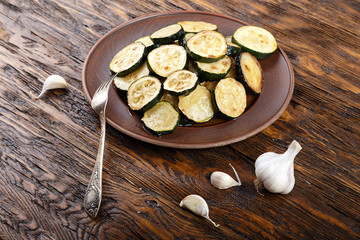 Fried zucchini in a clay plate on a wooden table