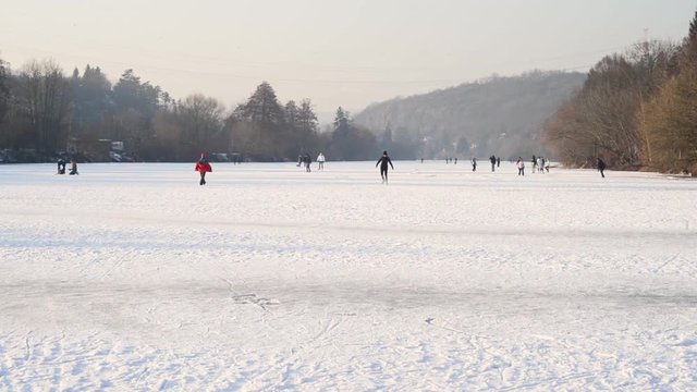 People crowds ice skating on a frozen winter river