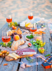 Fototapeta na wymiar Picnic on the beach at sunset in boho style, food and drink concept