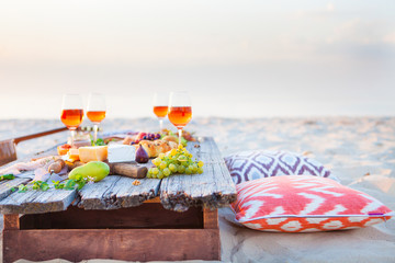 Picnic on the beach at sunset in boho style, food and drink concept