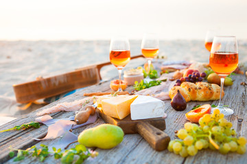 Picnic on the beach at sunset in boho style, food and drink concept