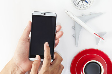 hand use smartphone with airplane model,red coffee cup and compass on white background.