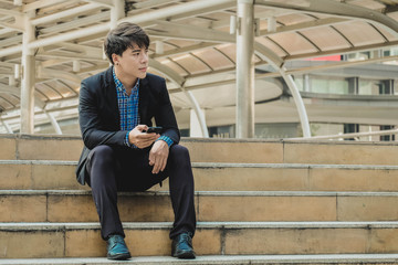 Portrait of handsome business man holding smartphone sitting or waiting for someone