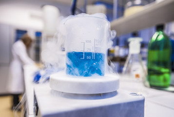 Blue liquid freezing in beaker with chemistry student at the back