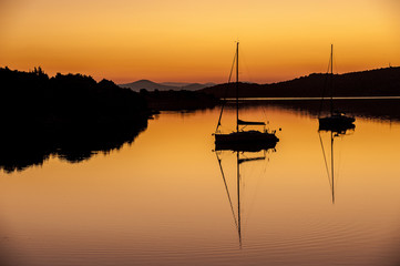 Two sailing boat in sunset, anchored in calm bay