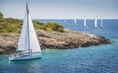 Obraz na płótnie Canvas White yacht sailing very close to island