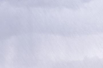 The texture of a strong incline rain against a background of light gray continuous clouds.