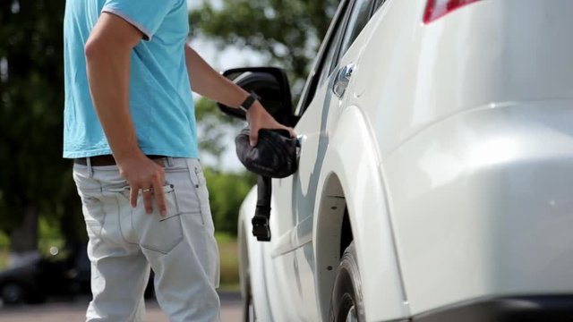 Man closes gas tank and gets into his car