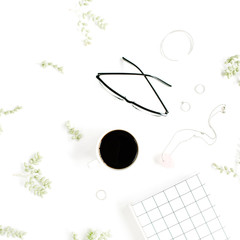 Coffee cup, notebook, glasses, green branches and female accessories on white background. Flat lay, top view