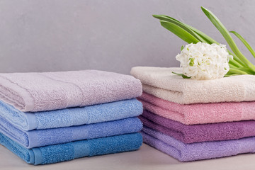 Obraz na płótnie Canvas Two stacks of colorful bath towels with hyacinth flower on light background.