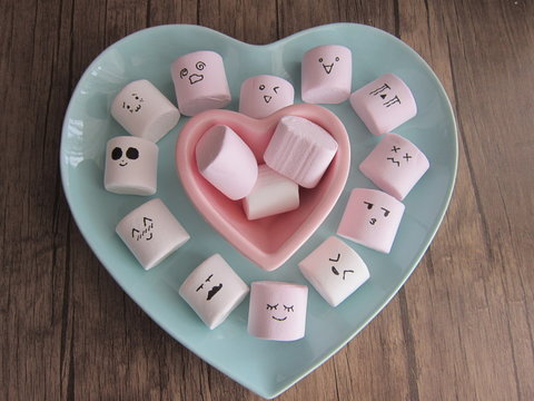 bowl of pink and white marshmallows on a wooden floor hearted