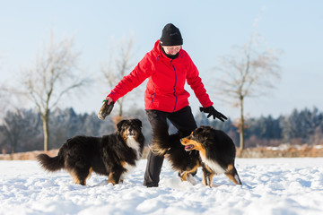 senior woman playing with dog in the snow