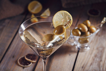 Glass of martini with green olives on a old wooden table