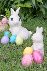 Easter bunny and Easter eggs, rabbit statues and colorful eggs at the backyard garden. Selective focus on the eyes of Easter bunny on the back