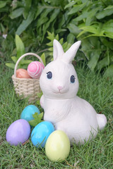 Easter bunny and Easter eggs, rabbit statues and colorful pastel eggs at the backyard garden. Soft focus on the eyes of Easter bunny. Easter eggs hunting activity concept.