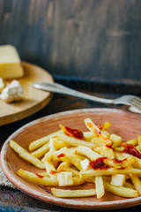 Poutine fries on black surface. Canadian dish with potatoes, cheese and sauce.