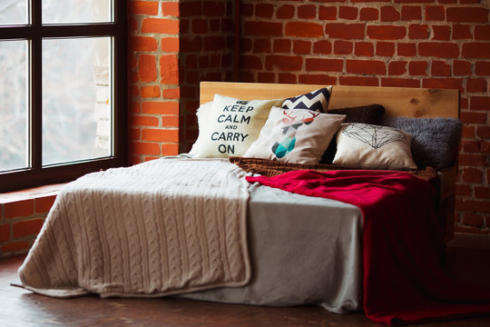 Beautiful loft bedroom with bed near brick wall and big window