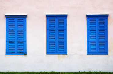 wall of old building and blue windows with shutters