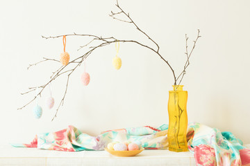 Branch with Easter eggs in a yellow vase.