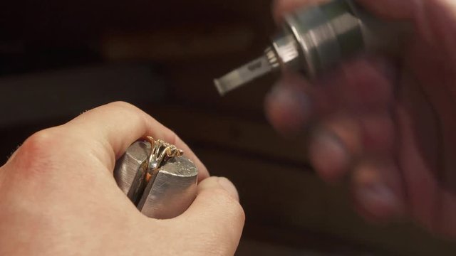 Caucasian man putting gemstone into the jewelry item. Macro close up of male hands prepares place for gem installation. Jeweller pushing zircon into the prong