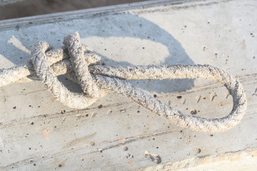 Tie rope placed on a concrete pole to be used to lift the concrete pole. During light shine causes a shadow of the knot.