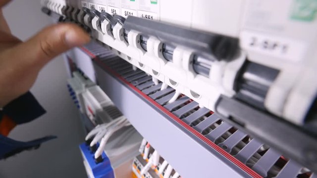 Professional electrician switch on electrical power, pushing switches in eletrical cabinets. 4K.