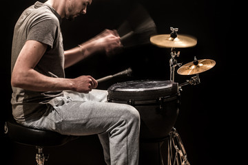 man playing a djembe drum and cymbals on a black background