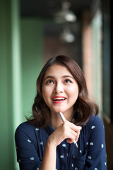 Young beautiful woman in the cafe near the window, thinking and writing something.