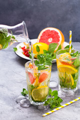 Cold refreshing summer lemonade in a glass on a grey concrete or stone background.