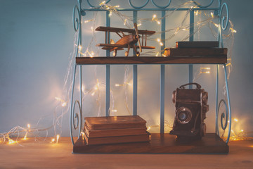 Vintage shelf with old wooden plane toy, books and decorative camera