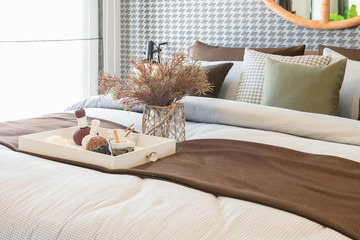 glass vase of plant with wooden tray on luxury bed in luxury bedroom